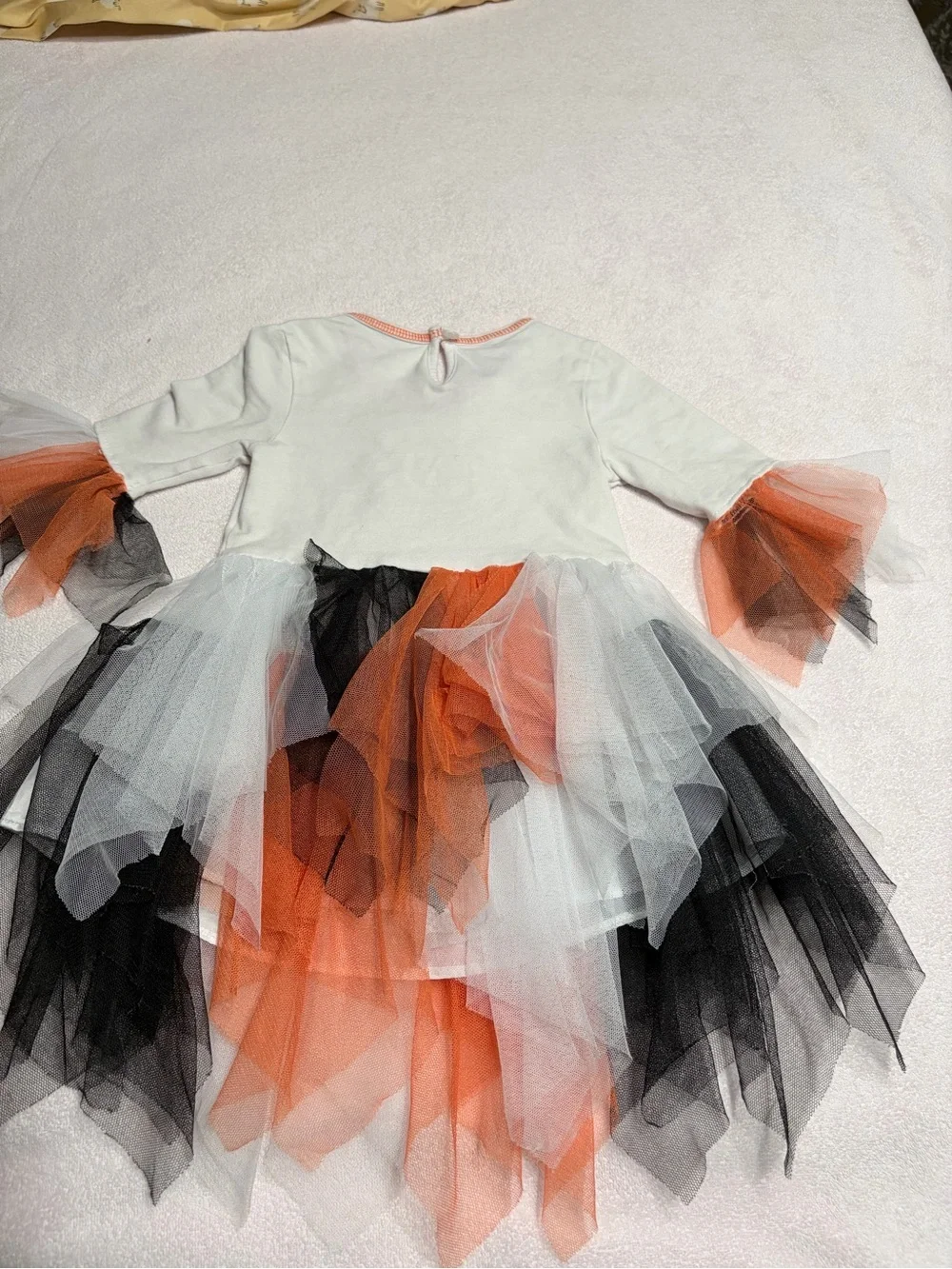 Cutie Halloween costume Has orange, black, and white tulle skirt and wrists.